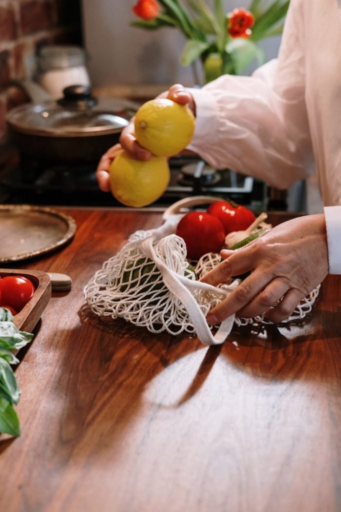 Hands arranging fresh vegetables and lemons on a kitchen table, highlighting home cooking.